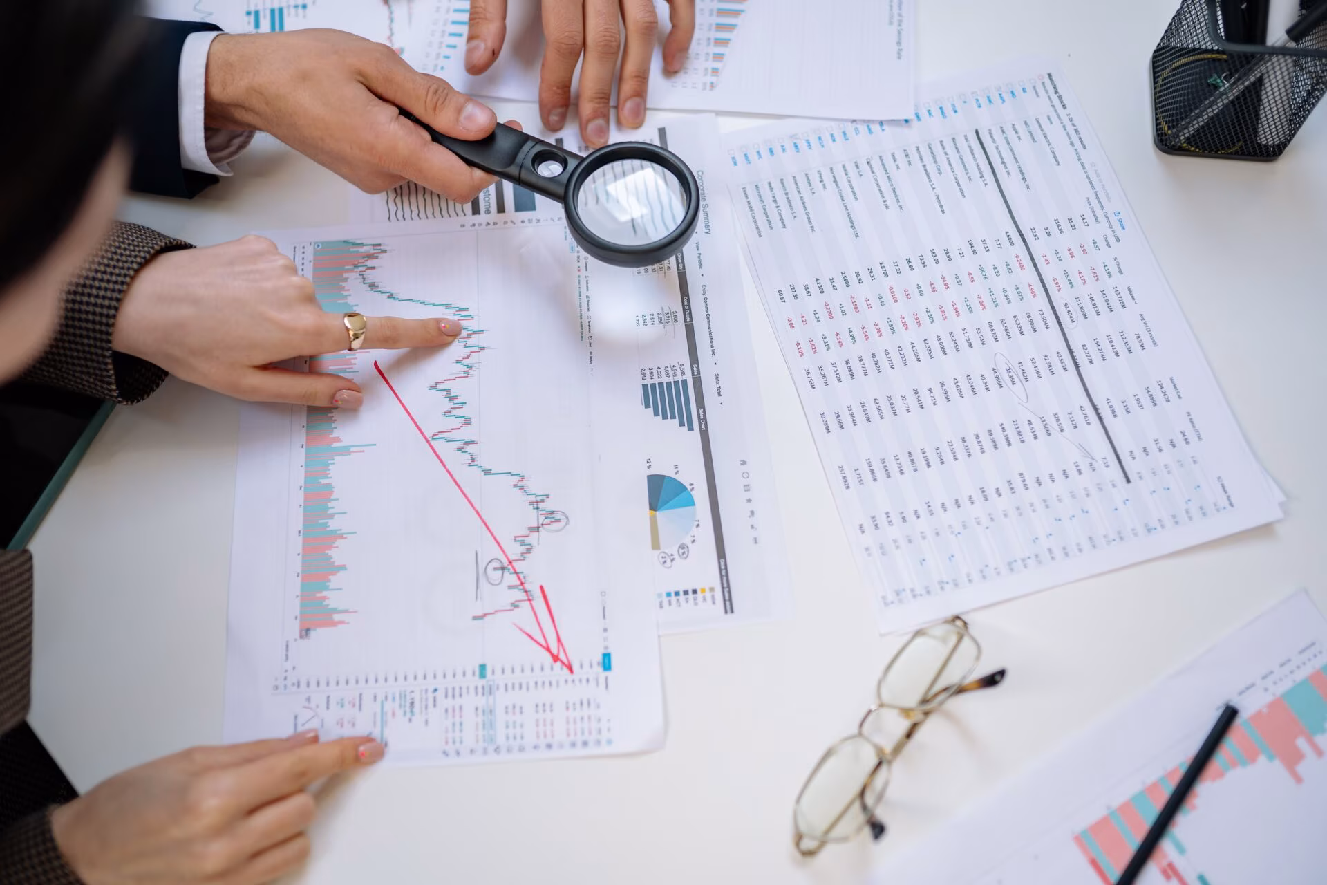 Reviewing financial documents and charts with a magnifying glass